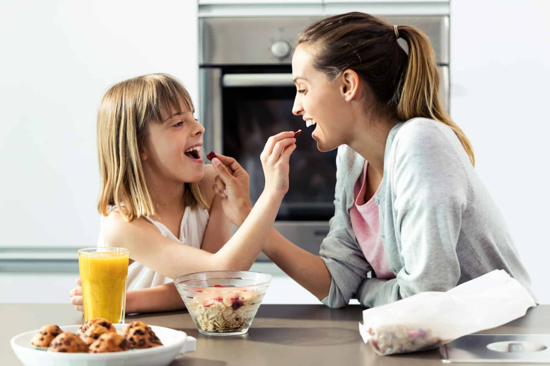 gesundkost, cerealien, mutter und tochter füttern sich gegeseitig